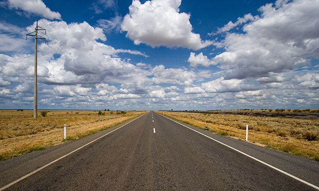 A photograph shows an empty road that continues toward the horizon.